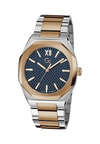 Vyriškas laikrodis su nerūdijančio plieno ir rožinio aukso akcentais. Aštuonkampis korpusas, mėlynas tekstūruotas ciferblatas, sidabro spalvos valandų žymekliai ir metalinė apyrankė.