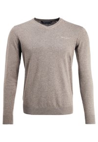 Grå v-ringad tröja i mjukt tyg. Långa ärmar, ribbad nederkant och manschetter, med en subtil logotyp på bröstet. Slät textur.