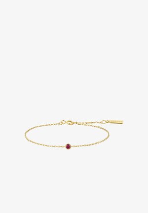 Bracelet délicat en chaîne d'or avec un petit centre de pierre précieuse ronde rose et un fermoir mousqueton, comportant une étiquette rectangulaire gravée "ANIA MAJE".