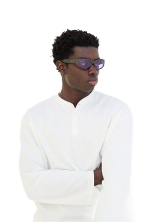 Occhiali da sole con un design elegante e angolare, lenti viola scuro e montatura nera opaca. Indossati con una maglietta a maniche lunghe bianca.