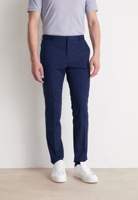 Merenpintaiset slim fit -housut, valmistettu liukkaasta kankaasta. Omistaa sivutaskut, vyölenkit ja on yhdistetty valkoisiin tennareihin.