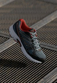 Meeste jooksujalats hallist võrgust punaste aksentidega, millel on pehme talla, must kummist välistald ja dekoratiivsed küljeribad.