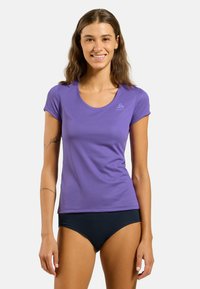Purple athletic T-shirt with short sleeves, round neckline, smooth texture, featuring a subtle logo on the chest. Paired with black swim bottoms.
