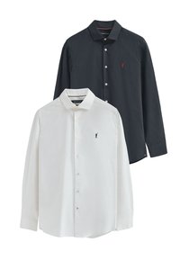 Camicie a maniche lunghe in cotone navy e bianco, con colli button-down e ricamo del logo sul petto. Ognuna ha bottoni lungo la parte anteriore.