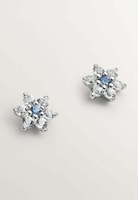 Pendientes de studs florales de plata con una piedra azul central rodeada de piedras preciosas claras, con un acabado pulido y disposición en forma de pétalos.