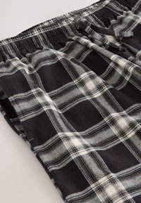 Sort-hvid ternet stof med en blød tekstur, elastisk taljebånd og snøre, der har skiftevis brede firkanter og fine linjer.