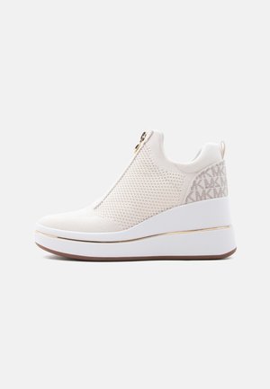 Hvit strikket kileformet sneakers med gullfarget glidelås foran, merket stoffpanel på hælen, og tykk hvit såle med gullkant.