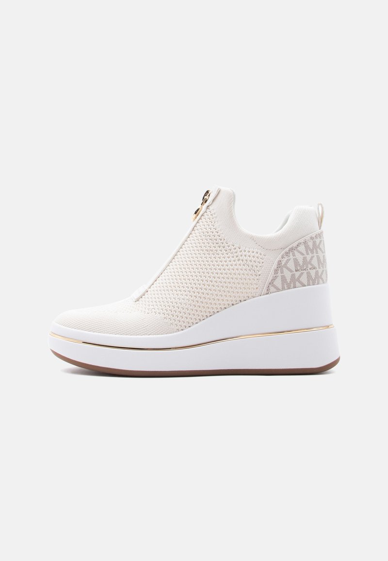 Λευκό πλεκτό αθλητικό παπούτσι με σφήνα, χρυστό φερμουάρ στο μπροστινό μέρος, πάνελ τακουνιού από υφασμάτινο υλικό με λογότυπο και χοντρή λευκή σόλα με χρυσό περίγραμμα.