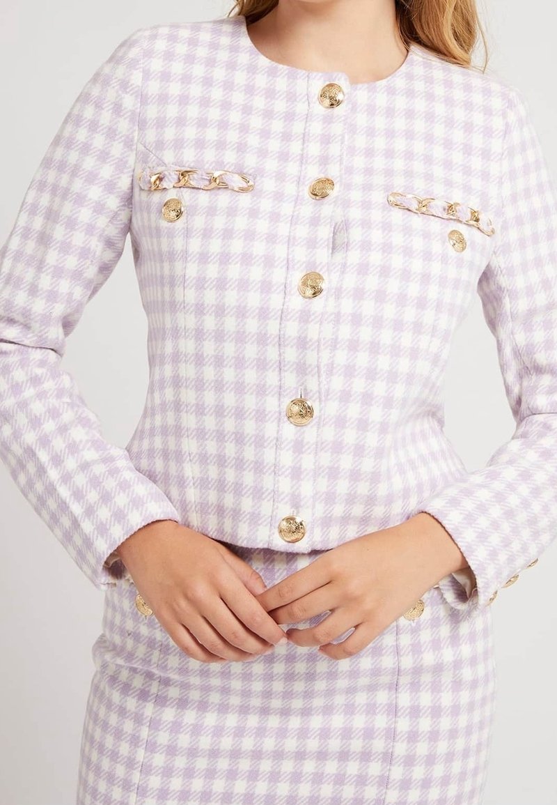 Chaqueta a cuadros lavanda en tejido texturizado, con botones dorados y detalles de cadena, con un escote redondo y dos bolsillos en el pecho.