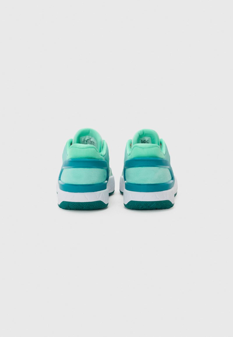 Chaussures de sport avec une tige turquoise, une semelle blanche et une texture adhérente sur la semelle extérieure. Matériau lisse et respirant au niveau du talon.
