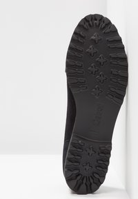 Semelle d'une chaussure noire avec des motifs profonds et la marque "Gabor" embossée au centre en bas.