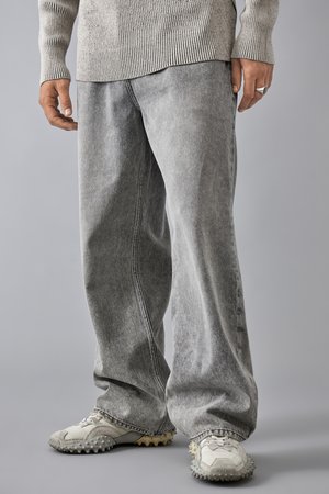 Bredde ben grå denim jeans med en falmet finish, med kontrastsøm og en avslappet passform, paret med teksturerte grå treningssko.