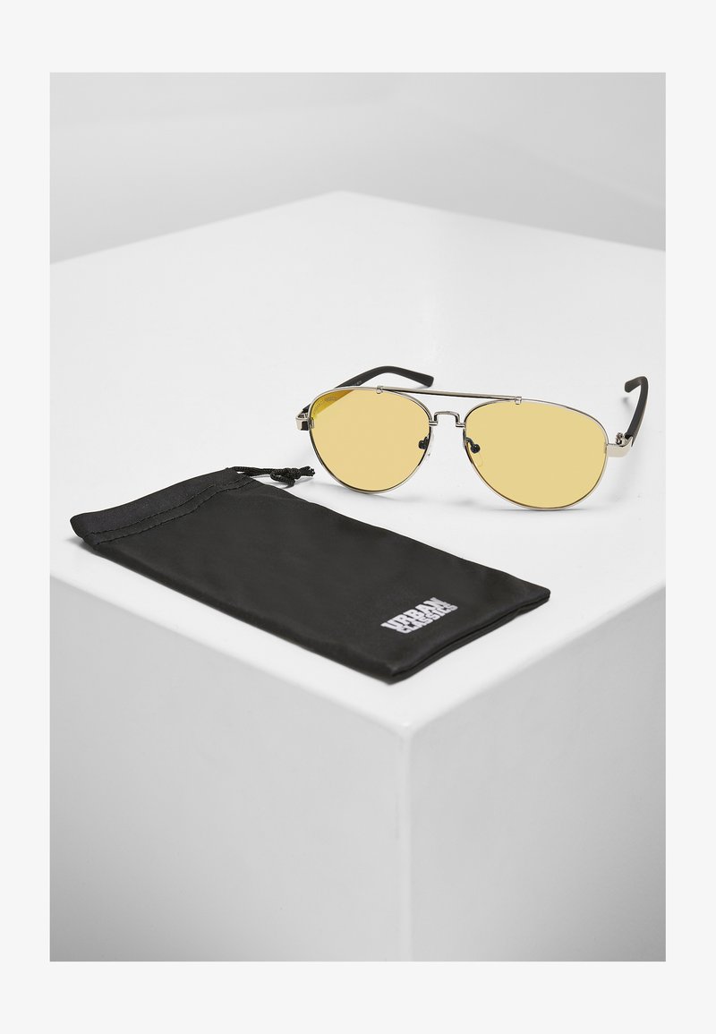 Stiilsed prillid kollaste läätsedega, metallraamiga ja mustade plastikust käepidemetega, kaasas must kangast kandmiskott.