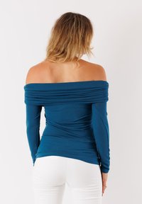 Top off-the-shoulder a maniche lunghe in tessuto verde scuro con dettagli arricciati. Texture liscia; design aderente che esalta la silhouette.