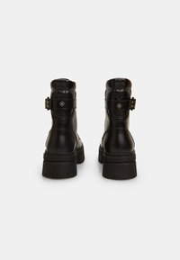 Botine nere in pelle liscia con un design trapuntato sul retro, dotate di una fibbia laterale e suole in gomma spesse.