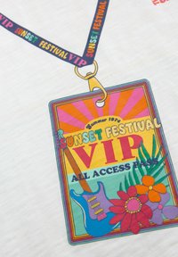 VIP piekļuve lanku pasei Sunset Festival, ar spilgtām krāsām, ģitāras grafiku, ziedu akcentiem un āķi augšpusē, uz baltas fona.