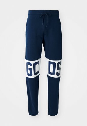 Marine bukser med elastisk liv og snøring. Har store hvite bokstaver "GC" og "OS" på kontrasterende paneler. Ribbestrikkede ankler.
