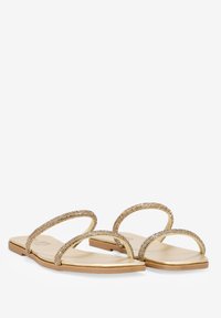 Las sandalias planas doradas cuentan con dos correas brillantes, una suela metálica suave y un diseño minimalista con una suela de goma plana.