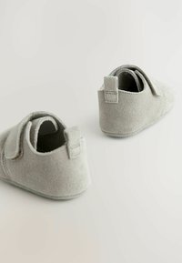 Grå mockaskor för spädbarn med rundad form, kardborrestängning och en liten hältab för enkel påklädning. Mjuk textur genom hela skon.