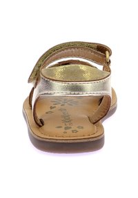 Sandalias color bronce con detalles metálicos dorados, suela plana y correa ajustable. La plantilla presenta un patrón floral.