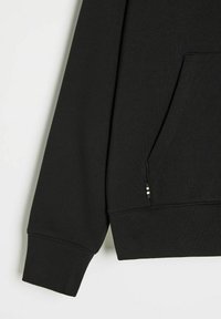 Czarna bluza z miękkim wykończeniem, długimi rękawami, przednią kieszenią i ściągaczem na dole z subtelnym paskiem po boku.