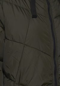 Tmavě zelená prošívaná bunda s černým zipem a černou šňůrkou viditelnou ve středu nahoře.