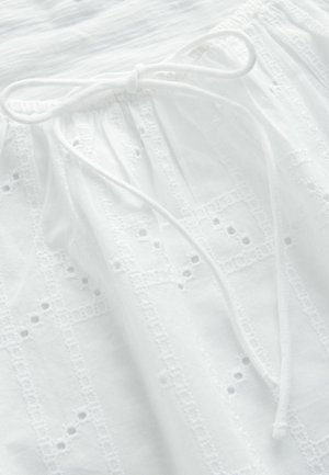 Baltos medvilnės drabužis su tekstūruotu, siuvinėtų raštų dizainu ir raišteliu juosmenyje. Audinys papuoštas subtiliais dekoratyviniais išpjovimais.