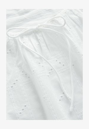 Fehér pamut ruházat, texturált, hímzett mintázattal és zsinóros derékrésszel. Finom díszítő kivágások találhatók az anyagon.