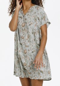 Robe à manches courtes et col en V en tissu vert clair avec motifs floraux et cachemire. Coupe ample avec fentes latérales, surface texturée et tombé souple.