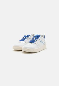 Baskets en cuir blanc avec des lacets et des accents bleus. Présentent des panneaux texturés, une semelle plate et un logo sur le côté. Design épuré dans l'ensemble.