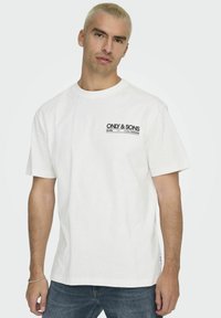T-shirt bianco in cotone con maniche corte. Presenta una stampa frontale sul petto in nero con "ONLY & SONS" e testo aggiuntivo. Vestibilità morbida.