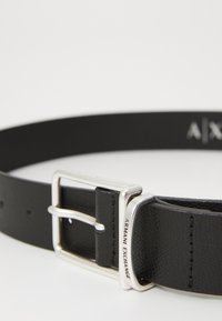 Black leather belt with a silver-tone buckle. Features a textured surface and embossed “Armani Exchange” logo on the buckle.