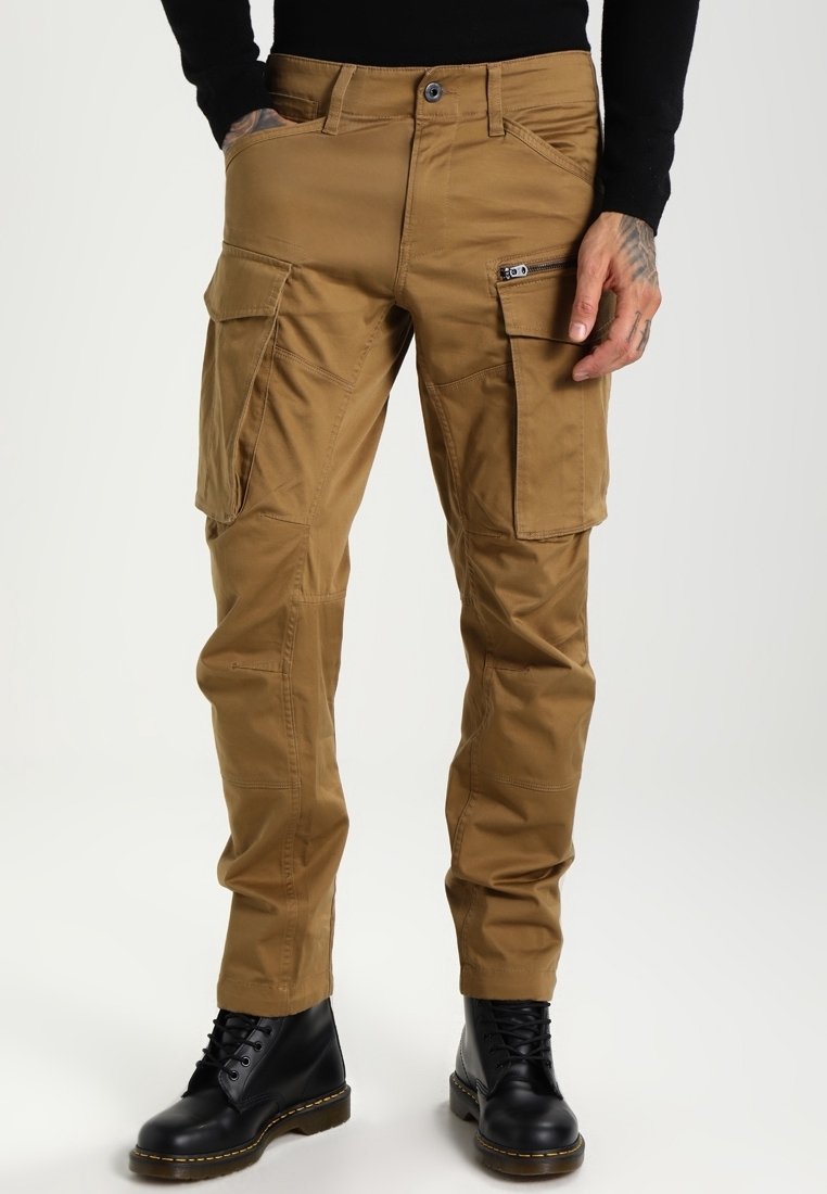 Cargo-housut khaki-värissä, valmistettu kestävästä kankaasta. Ominaisuuksiin kuuluu useita taskuja, sopiva vyötärö ja kapenevat lahkeet. Yhdistetty mustiin saappaisiin.