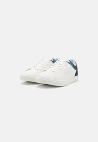 White sneakers with blue and orange accents, textured rubber sole, lace-up design, smooth synthetic upper, and logo detail on the side.