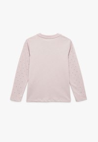 Langarm t-shirt van zacht roze katoen, met kleine zwarte en rode stippen op de mouwen. Eenvoudige ronde halslijn en een regular fit ontwerp.