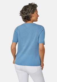 Hellblaues Kurzarm-Pullover mit Rundhalsausschnitt. Der Stoff wirkt weich und leicht strukturiert, hat eine lockere Passform und eine glatte Oberfläche.