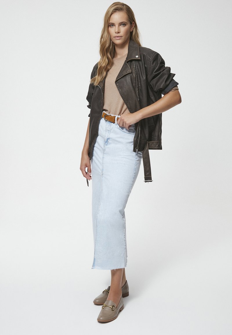 Brązowa skórzana kurtka motocyklowa, beżowa koszula, jasnoniebieska midi spódnica dżinsowa i szare mokasyny z detalem metalowym. Proste, czyste linie i tekstury.