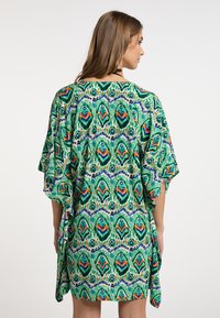 Kimono-stil dugačak s vibrantnim zelenim, plavim i narančastim geometrijskim uzorkom. Izrađen od lagane tkanine, ima široke rukave i slobodan kroj.