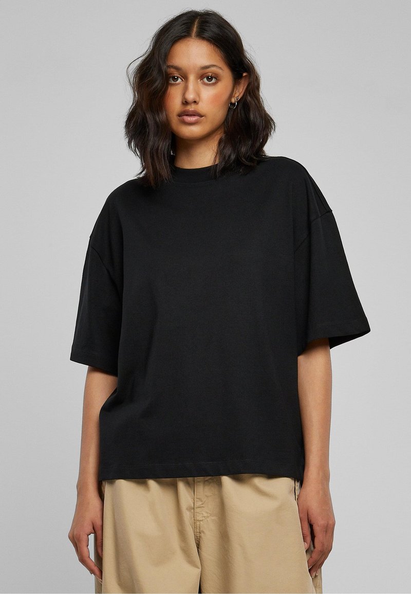 Svart oversized t-shirt i bomullstyg med rund halsringning och korta ärmar, med en avslappnad passform och minimalistisk design.
