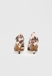 Chaussures à talons hauts avec un design à bout pointu, recouvertes d'un doux tissu beige avec un motif imprimé animal brun et de fins talons aiguilles.