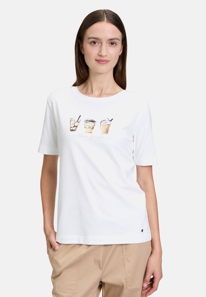 T-shirt en coton blanc avec un graphique à l'avant représentant quatre boissons au café illustrées. Manches courtes et col rond avec une coupe décontractée.