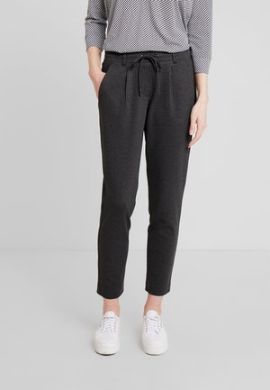 Donkergrijze broek met een geruite patroon, taps toelopende vorm, elastische tailleband met trekkoord, gecombineerd met witte sneakers en een zwart-wit gestreepte top.