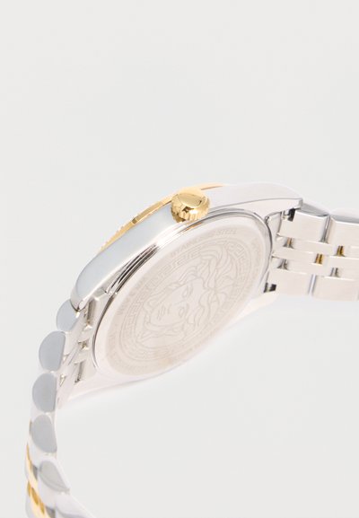 Ασημένιο και χρυσό μεταλλικό λουράκι ρολογιού με χρυσό στέμμα και χαραγμένο κεφάλι Μέδουσας στην πίσω θήκη του ρολογιού από ανοξείδωτο ατσάλι.