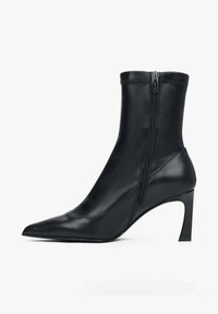 Černé kotníkové boty vyrobené z hladké kůže s špičatou špičkou a bočním zipem. Mají jehlový podpatek a těsný střih kolem kotníku.