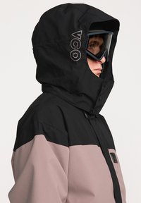 Zwarte en roze geïsoleerde jas met een gestructureerde capuchon, voorzien van een logo en knopen, en een gladde textuur die geschikt is voor buitengebruik.