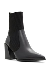 Botte de cheville noire avec une tige en tricot côtelé et un panneau en cuir lisse. Présente un bout pointu et un talon géométrique épais.