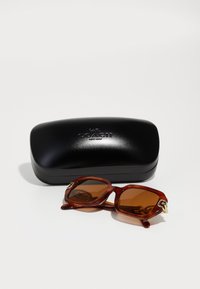 Ochelari de soare cu nuanță de marou, cu o ramă groasă, unghiulară, din scoică de broască țestoasă. Include un toc rigid negru cu un logo embosat.
