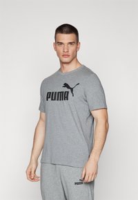 Grå kortærmet t-shirt med sort "PUMA" logo og katte-silhuet. Lavet af blødt stof, med rund halsudskæring og afslappet pasform.
