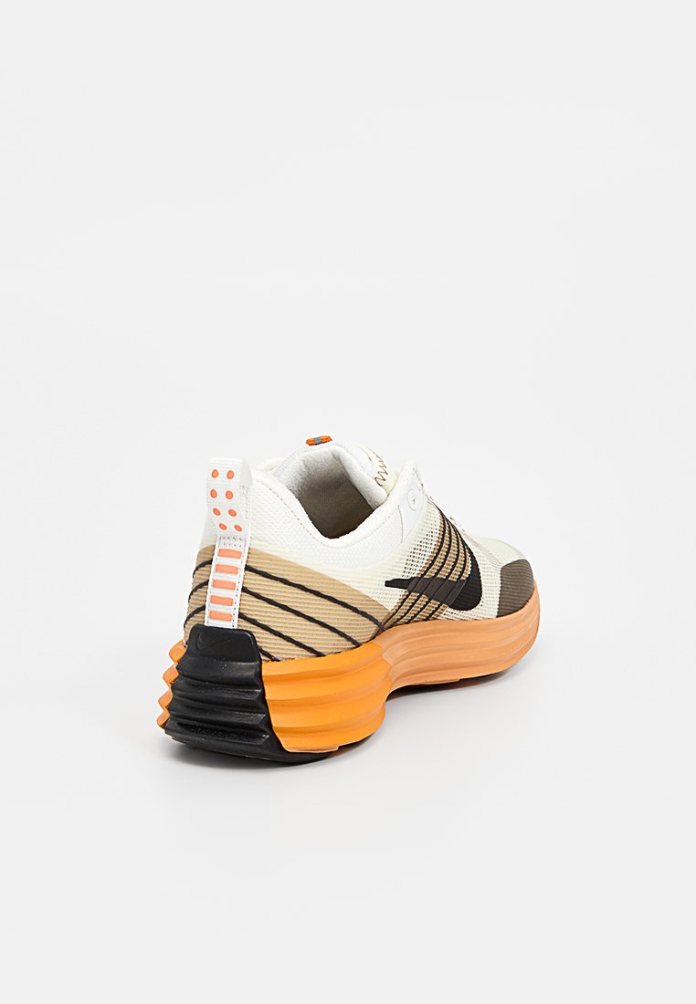 Sneaker con una toma superiore in rete bianca traspirante, accenti neri e arancioni, una suola arancione spessa e motivi a strisce diagonali sui lati.