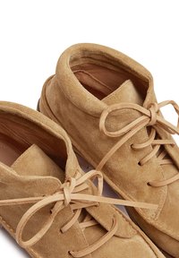 Zapatos de ante en color beige arena con puntas redondeadas, cordones de ante a juego y un interior suave. Diseño casual con costuras simples.